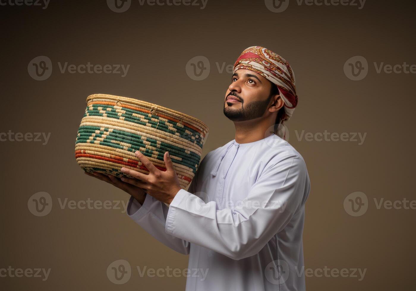 Man in Traditional Dress Holding Handcrafted Woven Basket Looking Upward photo