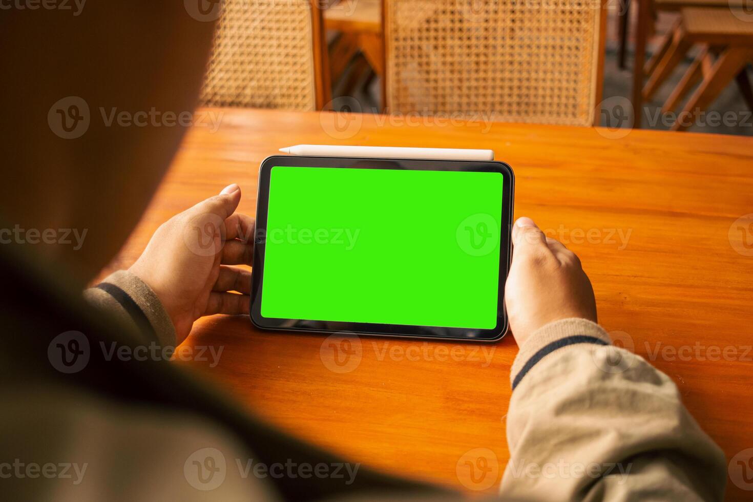 Close-up of hands using a tablet with a green screen, ideal for mockups or digital presentations. photo