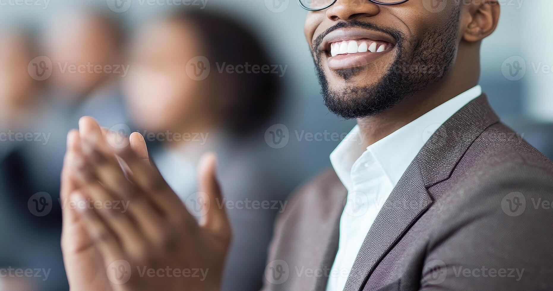 smiling man in suit claps his hands, showcasing positive atmosphere in professional setting. His expression reflects enthusiasm and engagement during meeting or presentation photo