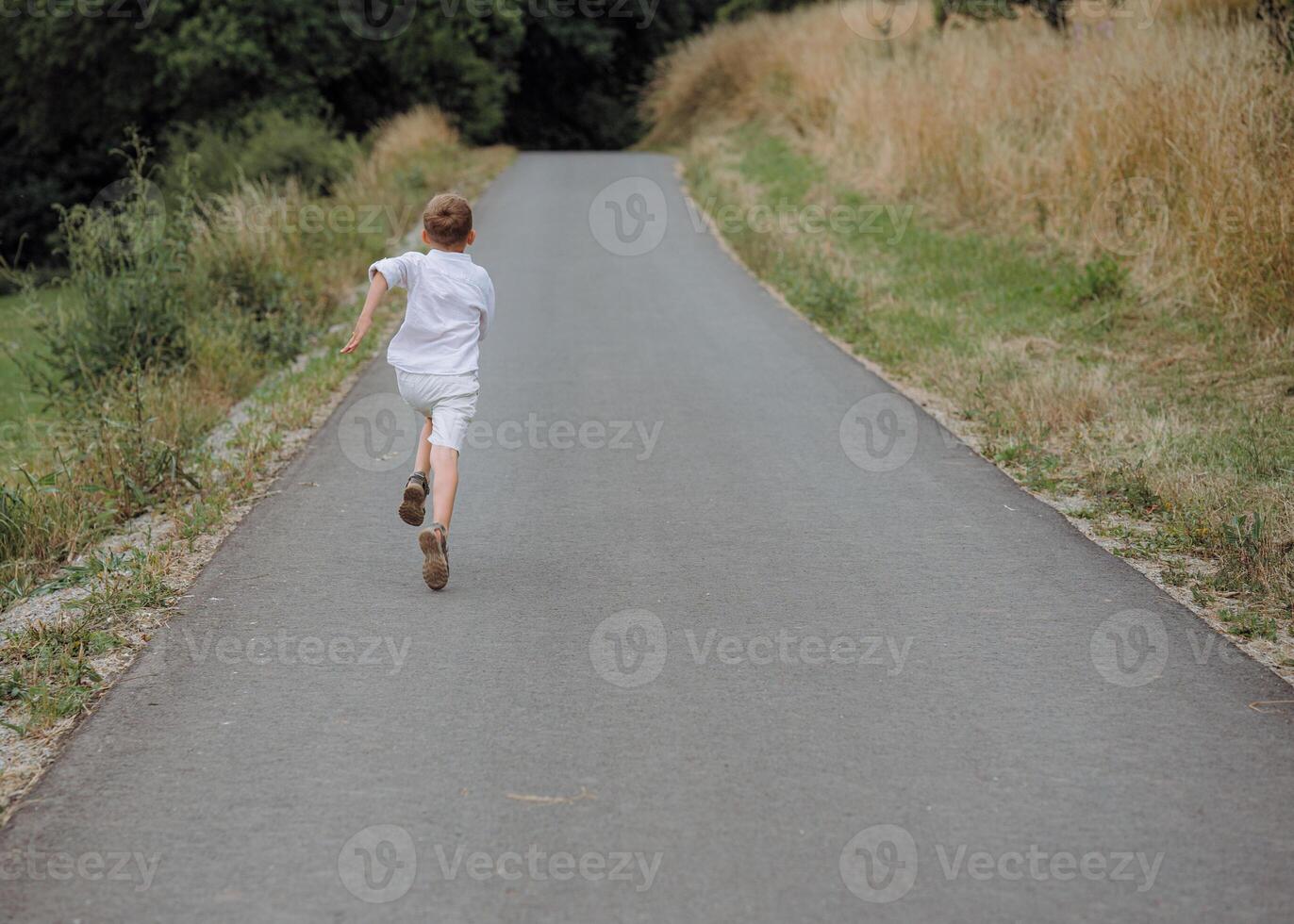 a boy running fast on the asphalt in the countryside in summer. photo