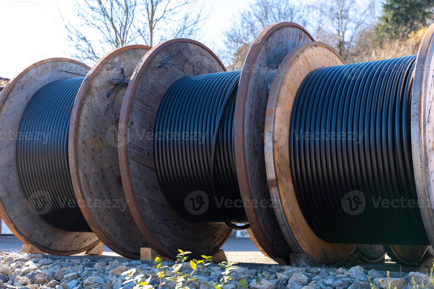 Large industrial reels with electrical cables are located at a construction site. They provide ease of installation and are used in energy and communication industries. photo