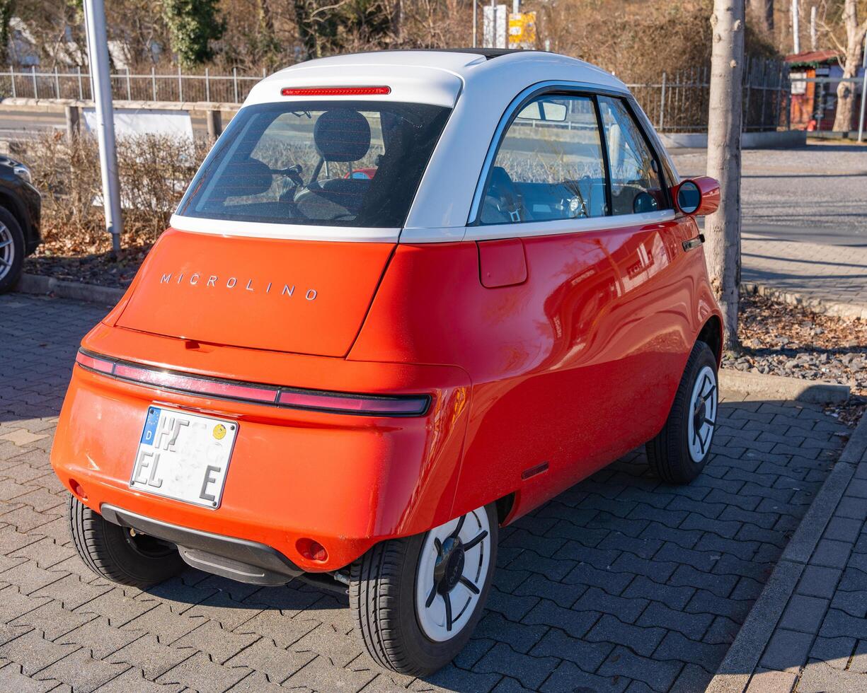 Bad Hersfeld, Germany, 03.02.2025 Italian red electronic car Microlino on a sunny day standing in a parking lot rear view photo