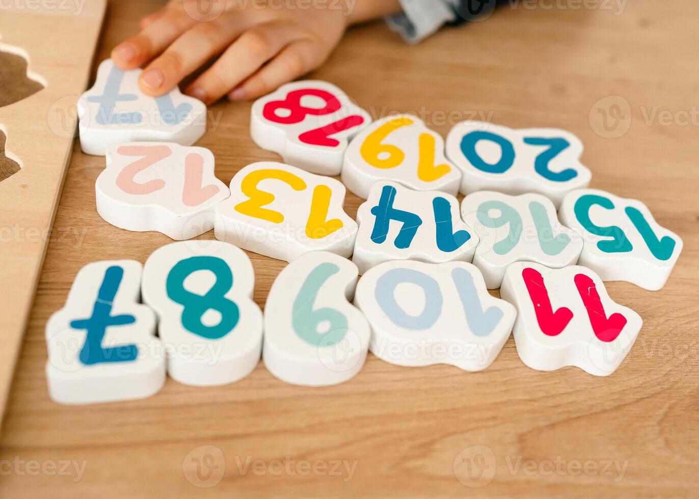 boy learns to count by laying out numbers from 1 to 20 on the board, boy 4-5 years old European appearance, at home in the living room sitting at the table, preparation for school photo