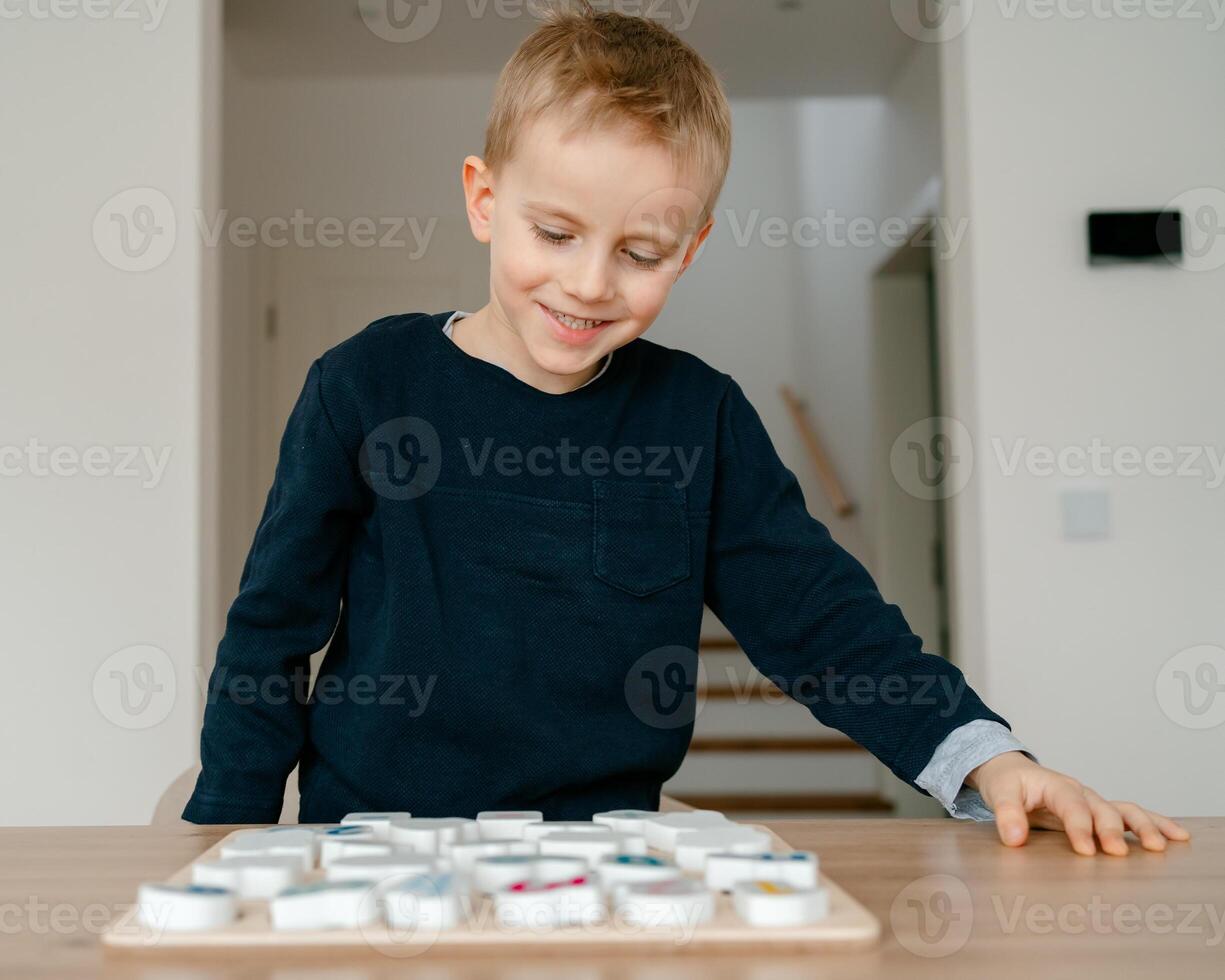 boy learns to count by laying out numbers from 1 to 20 on the board, boy 4-5 years old European appearance, at home in the living room sitting at the table, preparation for school photo