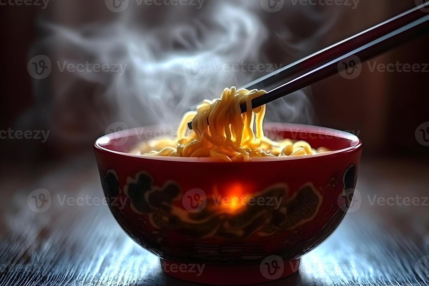 Steaming noodles lifted with chopsticks from a red bowl. photo