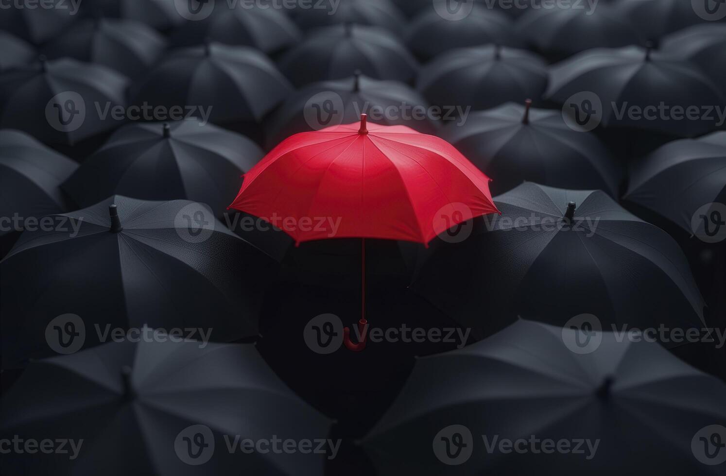Red umbrella standing out from the crowd of black umbrellas photo