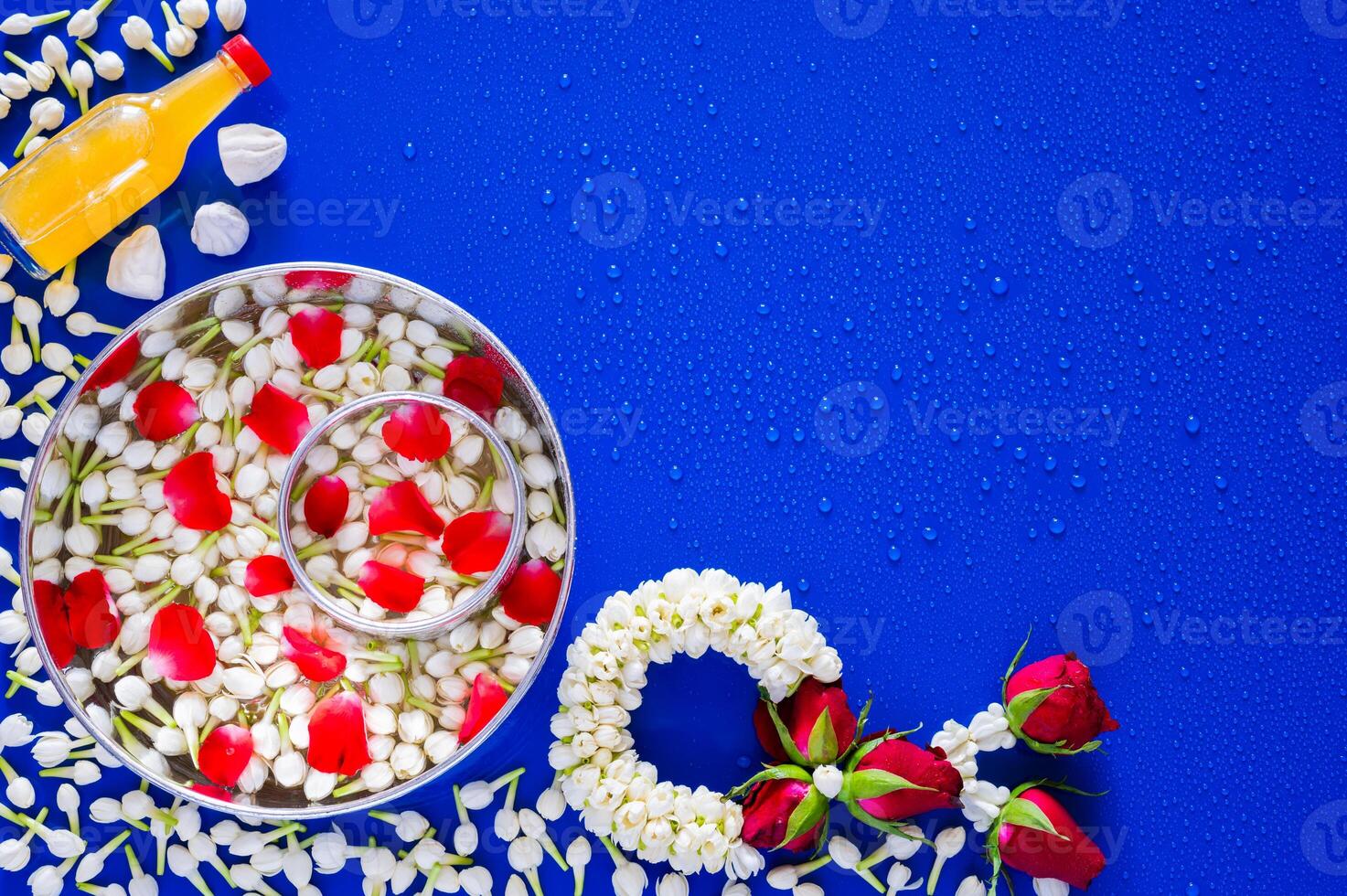 Flowers in water bowl for blessing, scented water and marly limestone with jasmine garland on wet blue background for Thailand Songkran festival background. photo