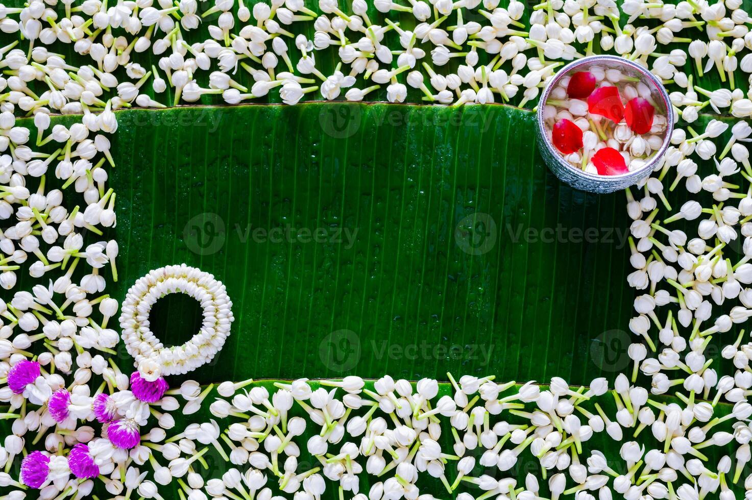 Flowers in water bowl for blessing with garland on empty space of wet banana leaf and jasmine background for Thailand Songkran festival background. photo