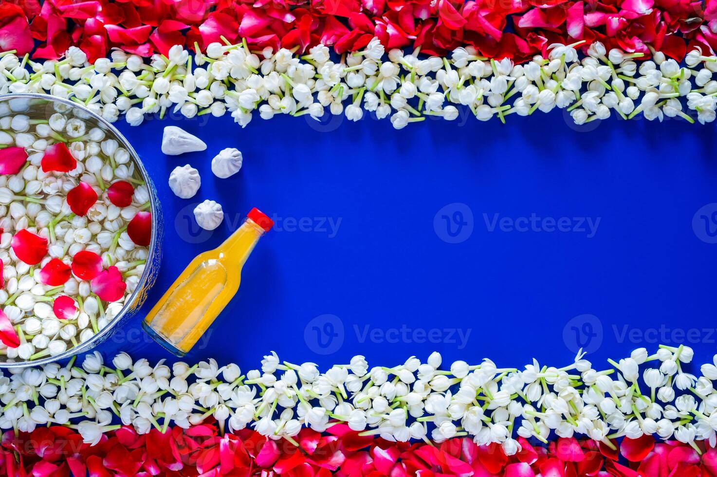 Flowers in water bowl for blessing with scented water and marly limestone on blue background with jasmine and red rose petal set as Thailand flag for Thailand Songkran festival background. photo