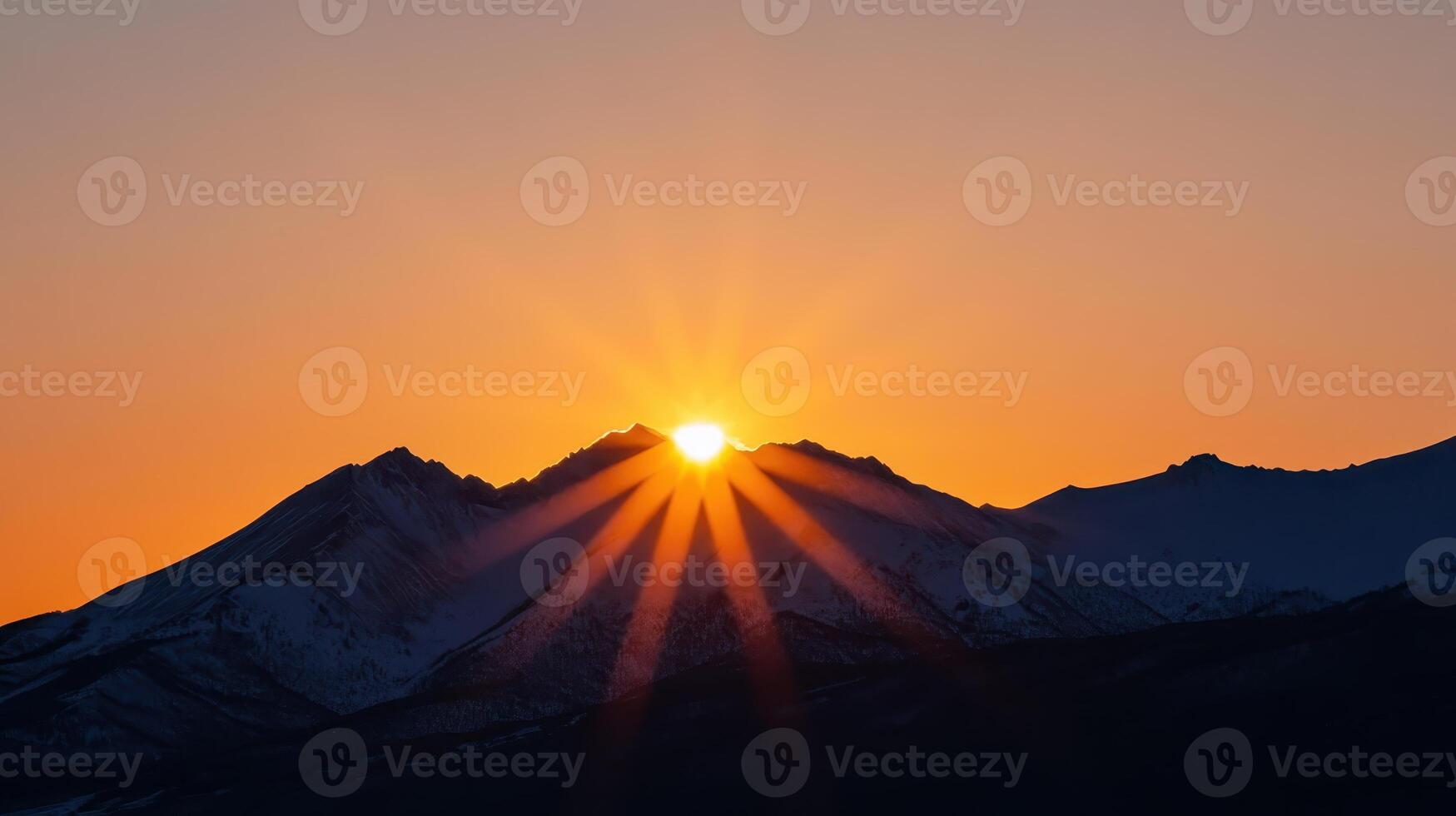 A breathtaking sunrise unfolds over the majestic mountains, with golden rays of light spilling across the landscape, illuminating everything beneath a clear, serene sky at the break of dawn photo