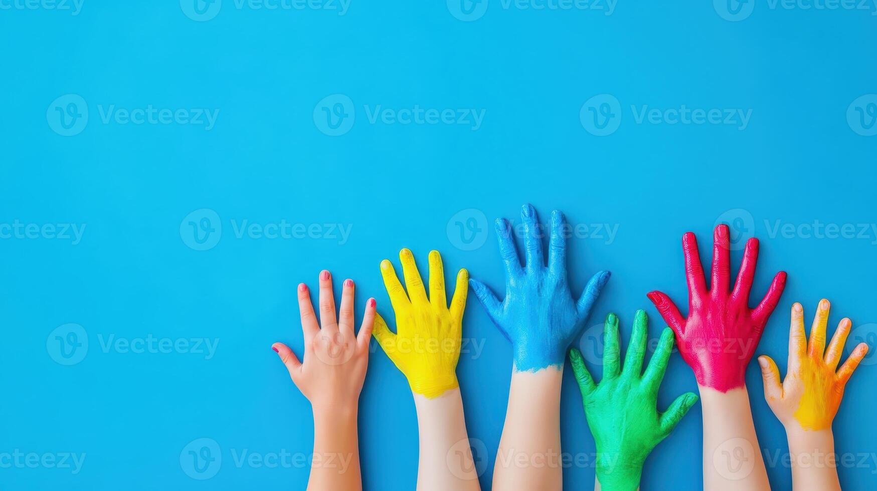 Colorful hands in vibrant shades displayed against a bright blue background during an artistic activity in a classroom setting photo
