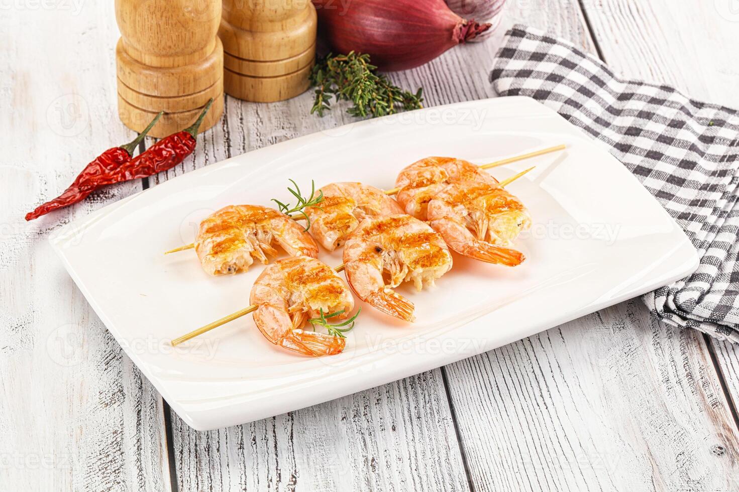 A plate with shrimp and vegetables on skewers photo