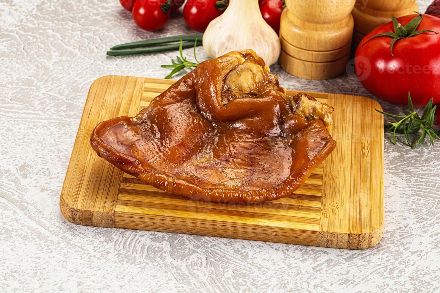 A piece of meat on a cutting board with a knife and garlic photo