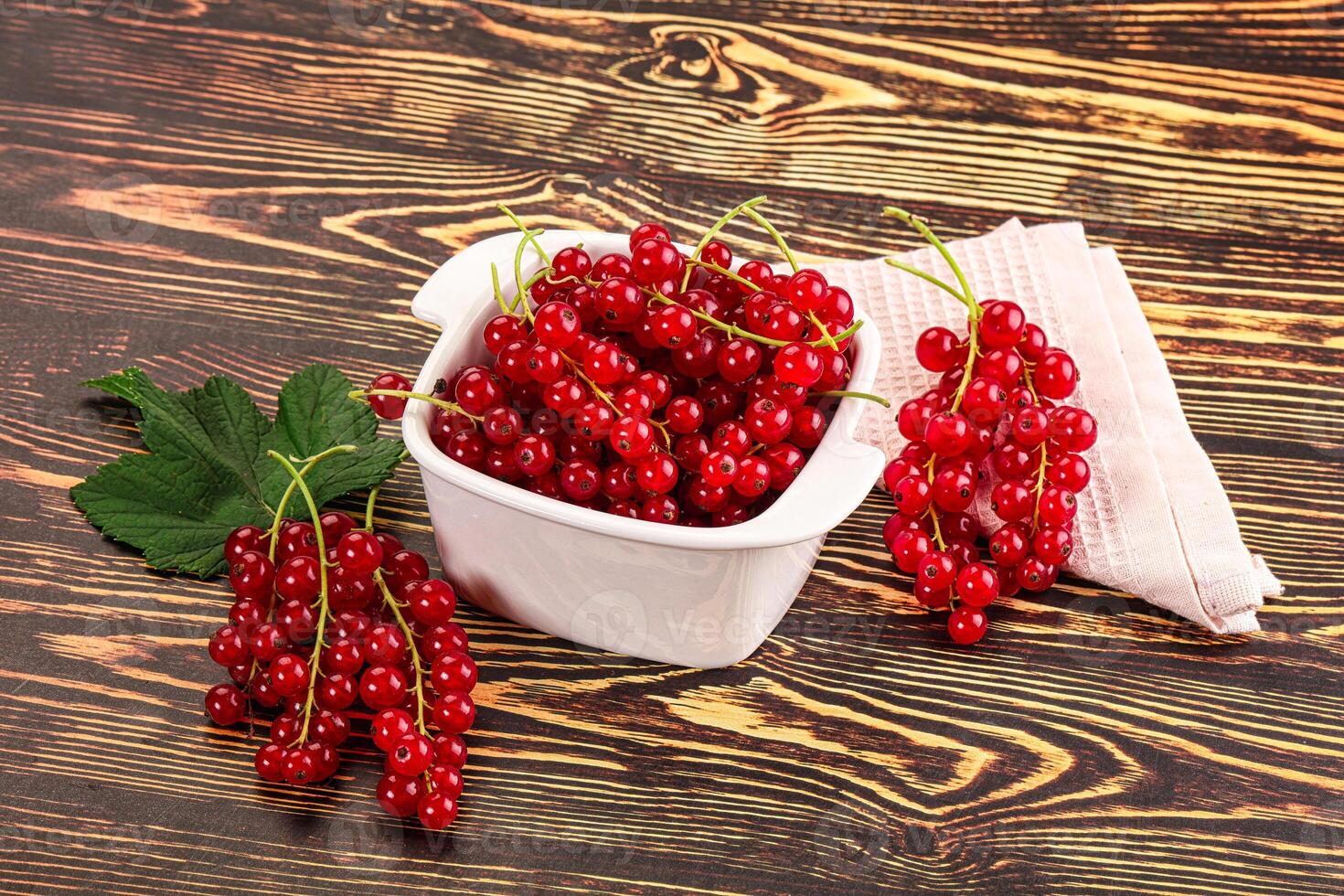A bowl of red currants on a wooden table photo