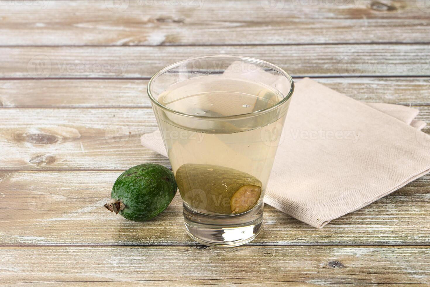 A glass of water with an avocado on a wooden table photo