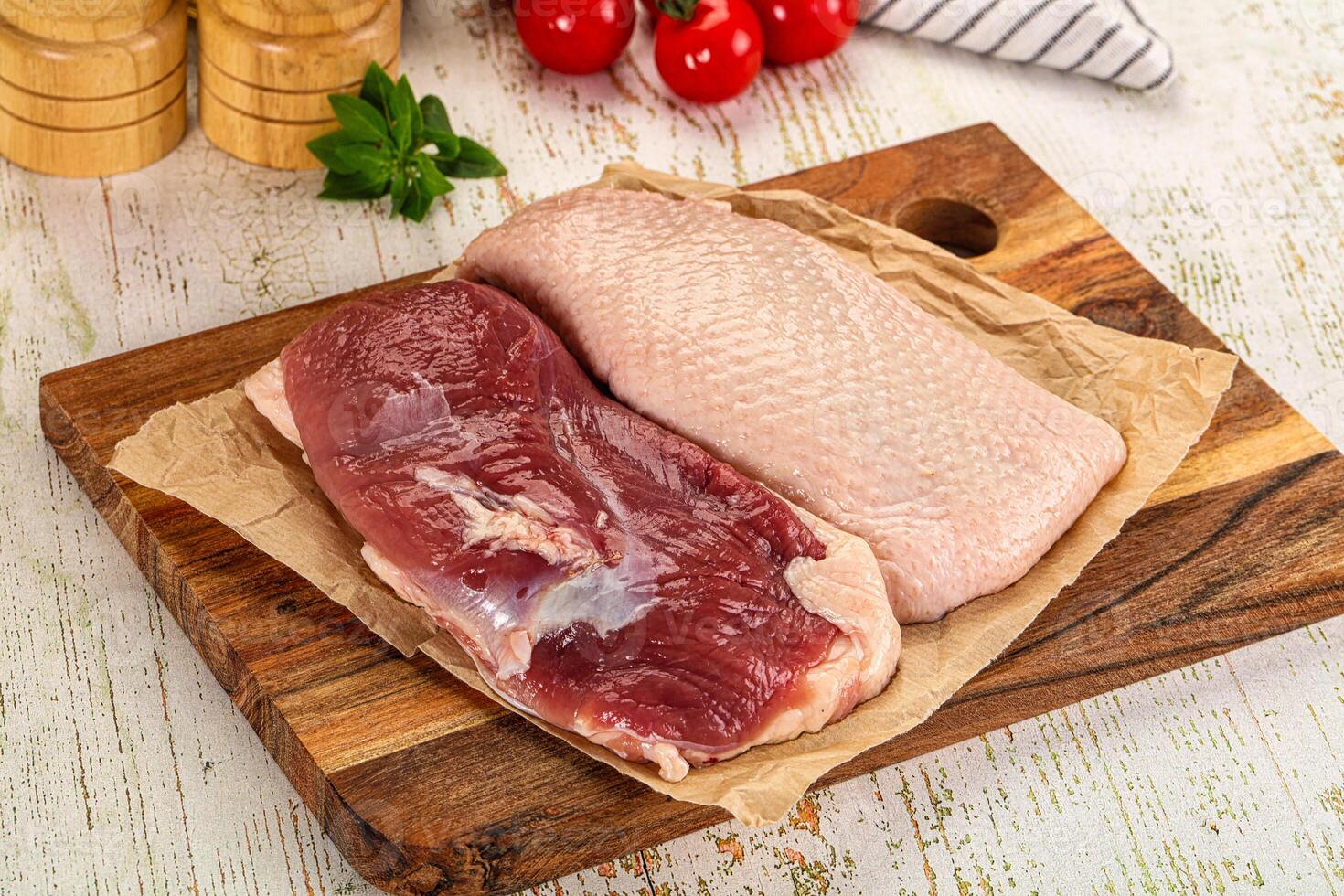 Two raw meat pieces on a cutting board with a knife and spices photo