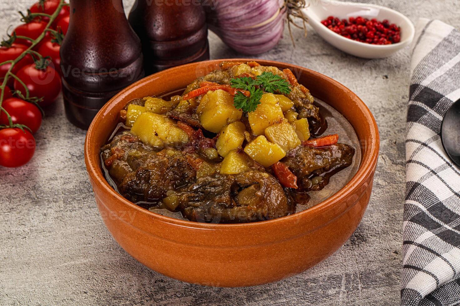 A bowl of stew with vegetables and tomatoes on a table photo