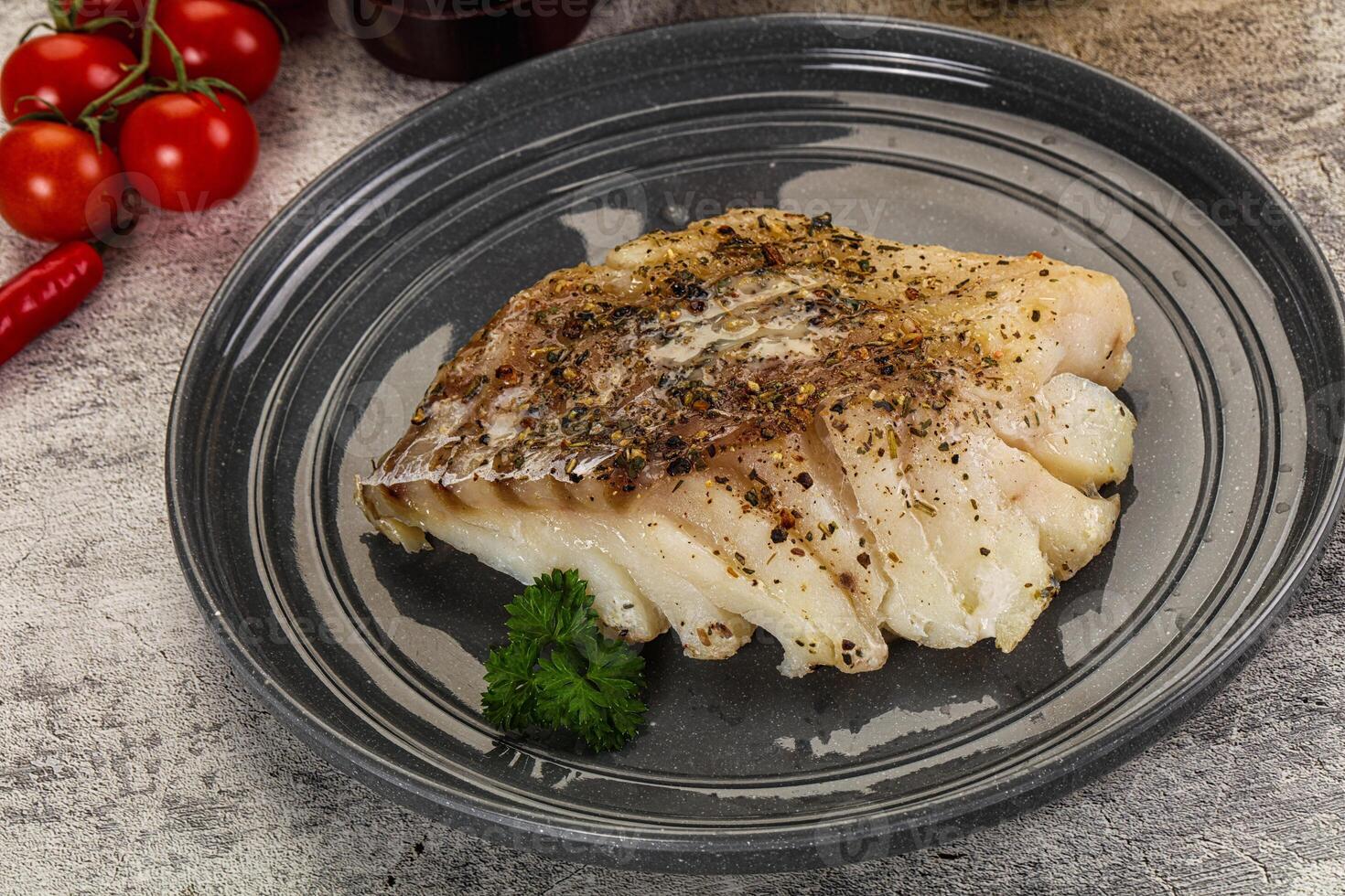 A piece of fish on a plate with tomatoes and spices photo