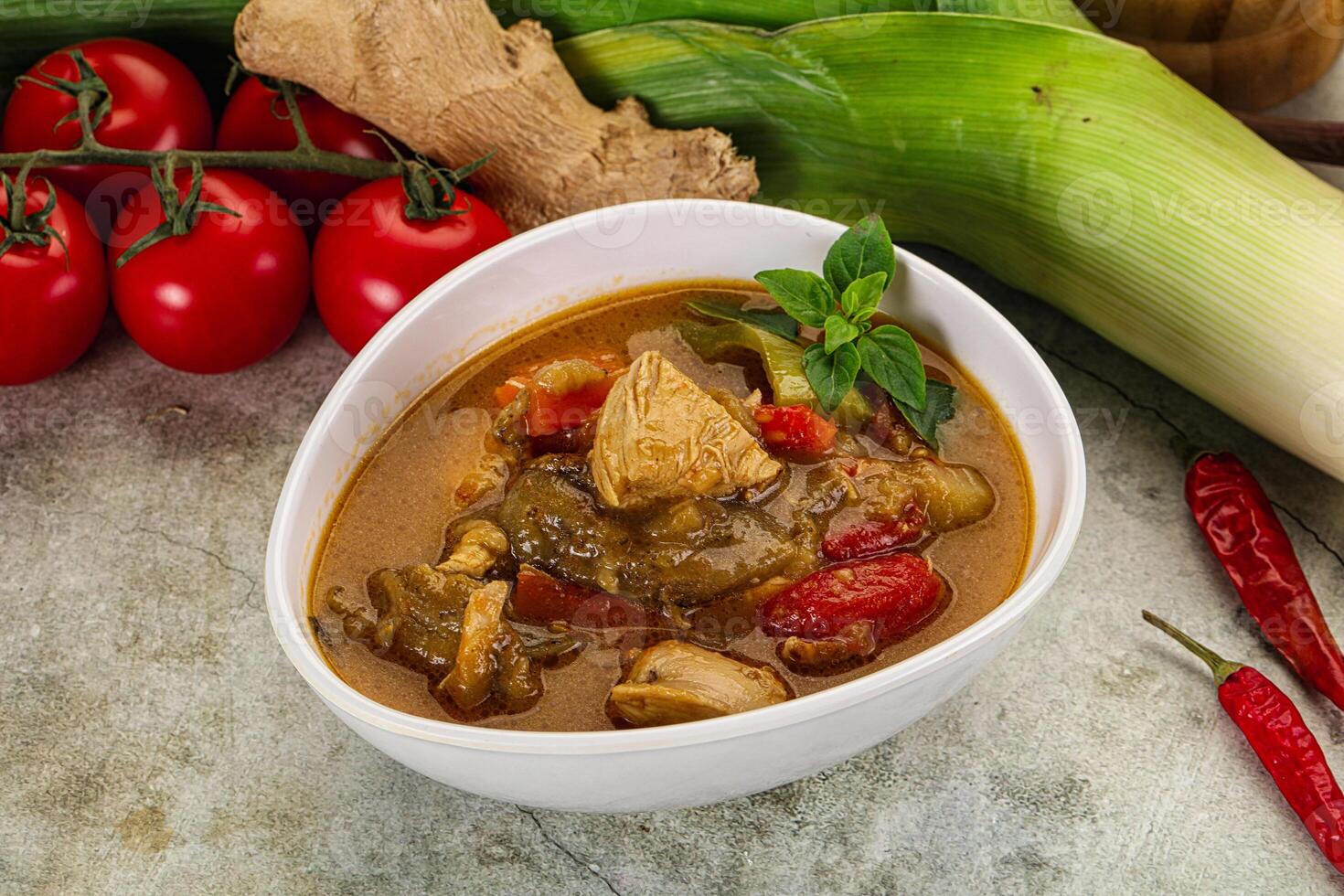 A bowl of curry with vegetables and tomatoes photo