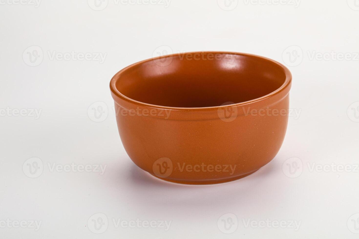 A small orange cup sitting on a white surface photo