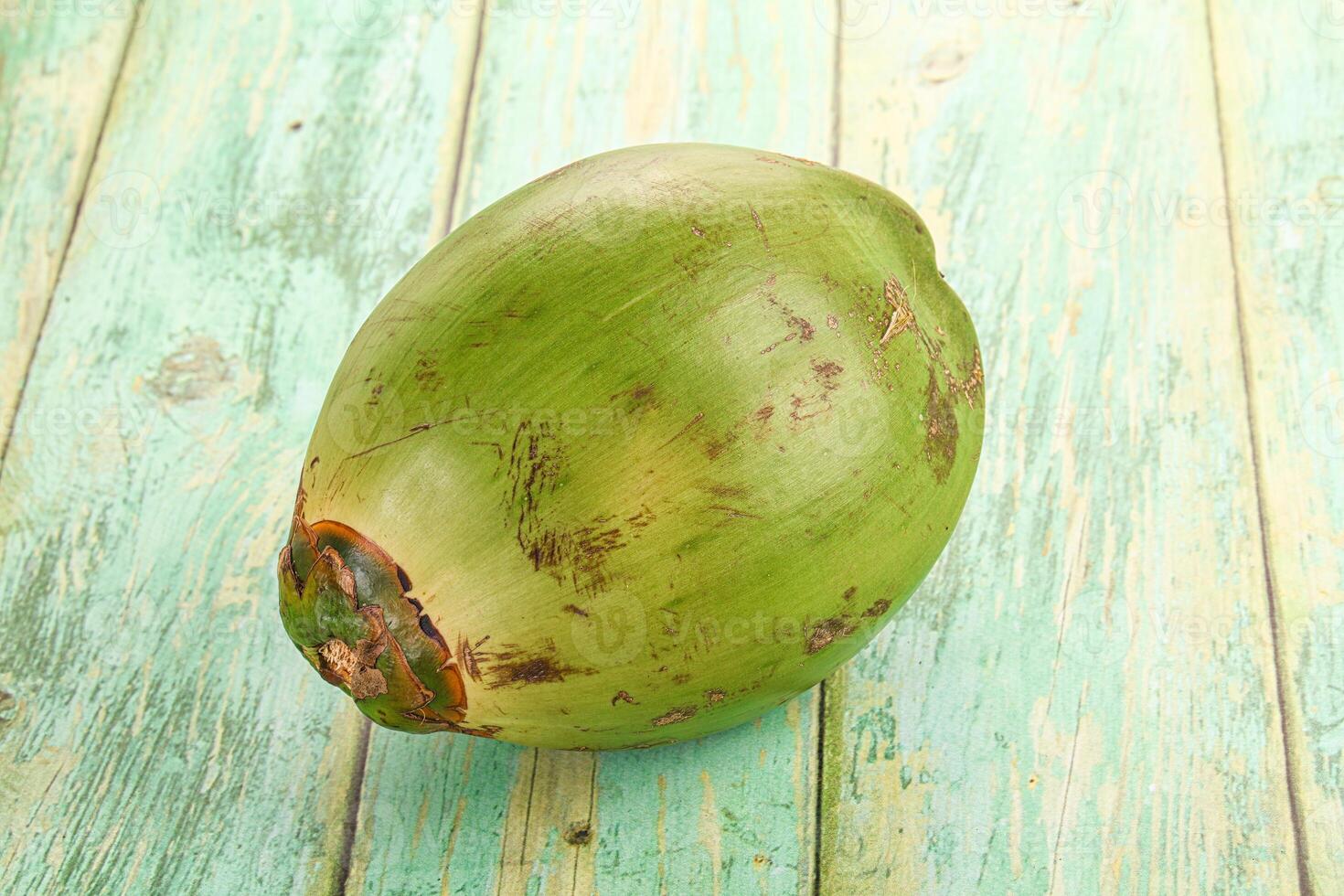 A coconut is sitting on a wooden table photo