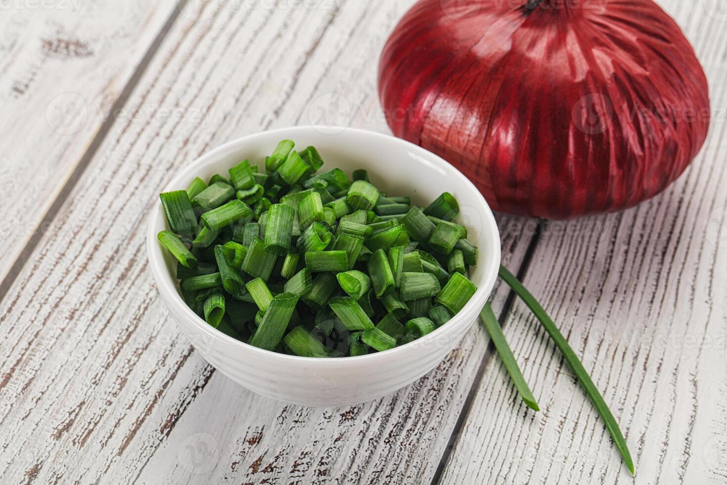 A bowl of chopped green onions and an onion photo