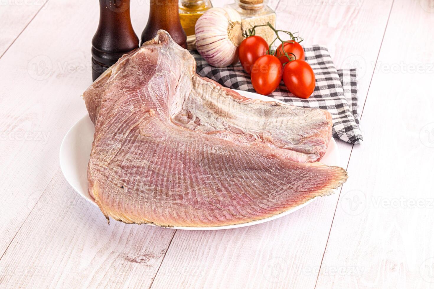 Raw fish on a plate with tomatoes and spices photo