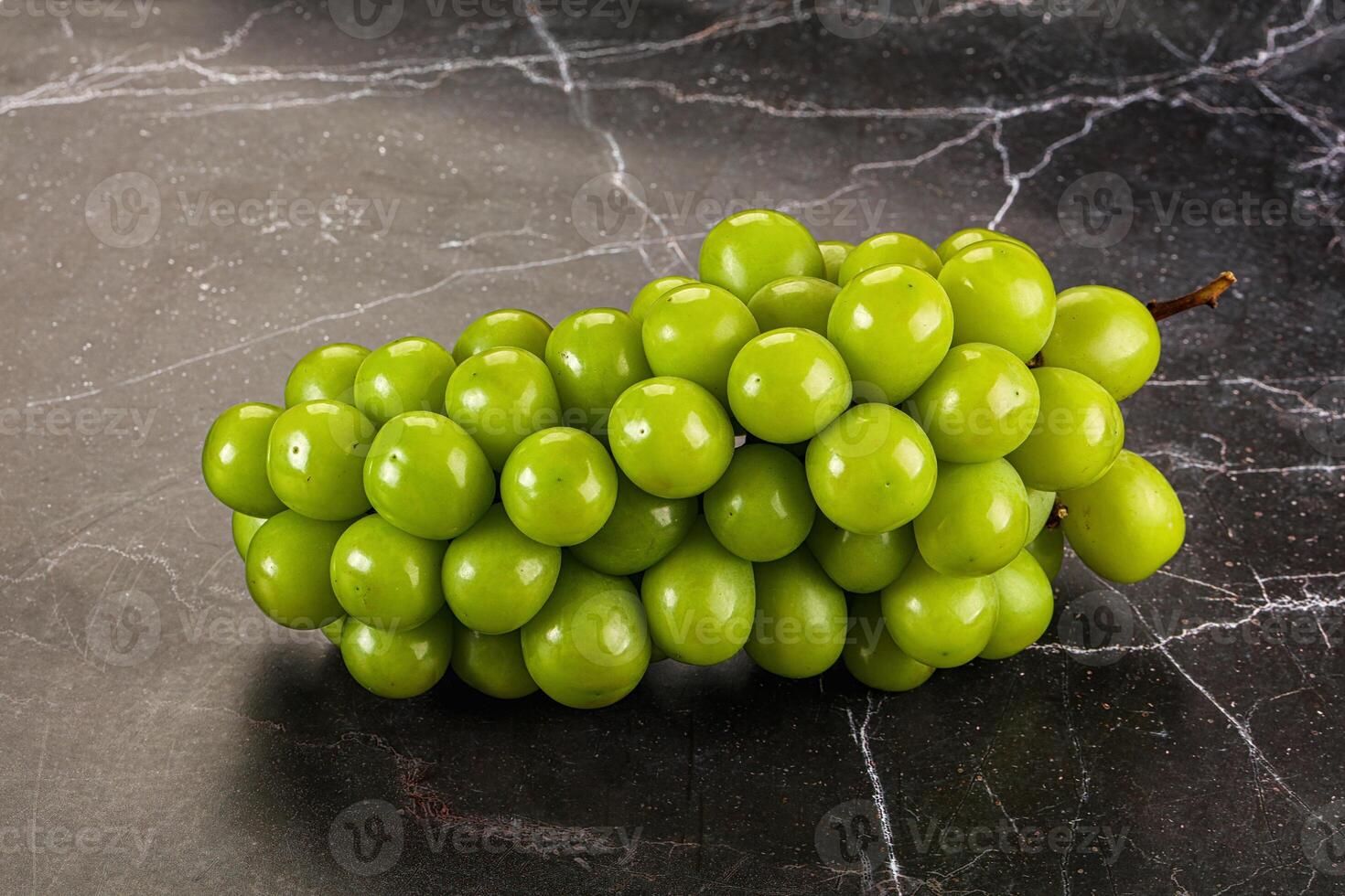 A bunch of grapes on a marble surface photo