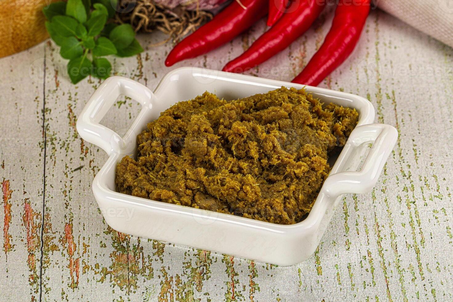 A bowl of green curry paste with red peppers and onions photo