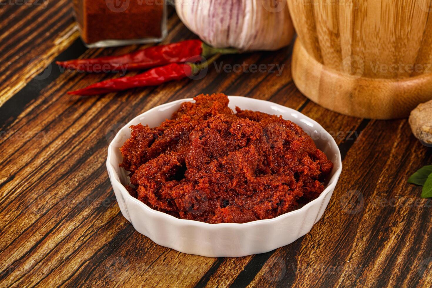 A bowl of red chili paste on a wooden table photo