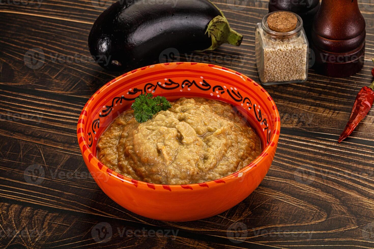 A bowl of hummus with a spoon and a pepper photo