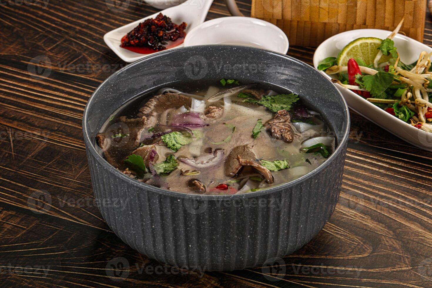 A bowl of soup on a table next to a bowl of salad photo