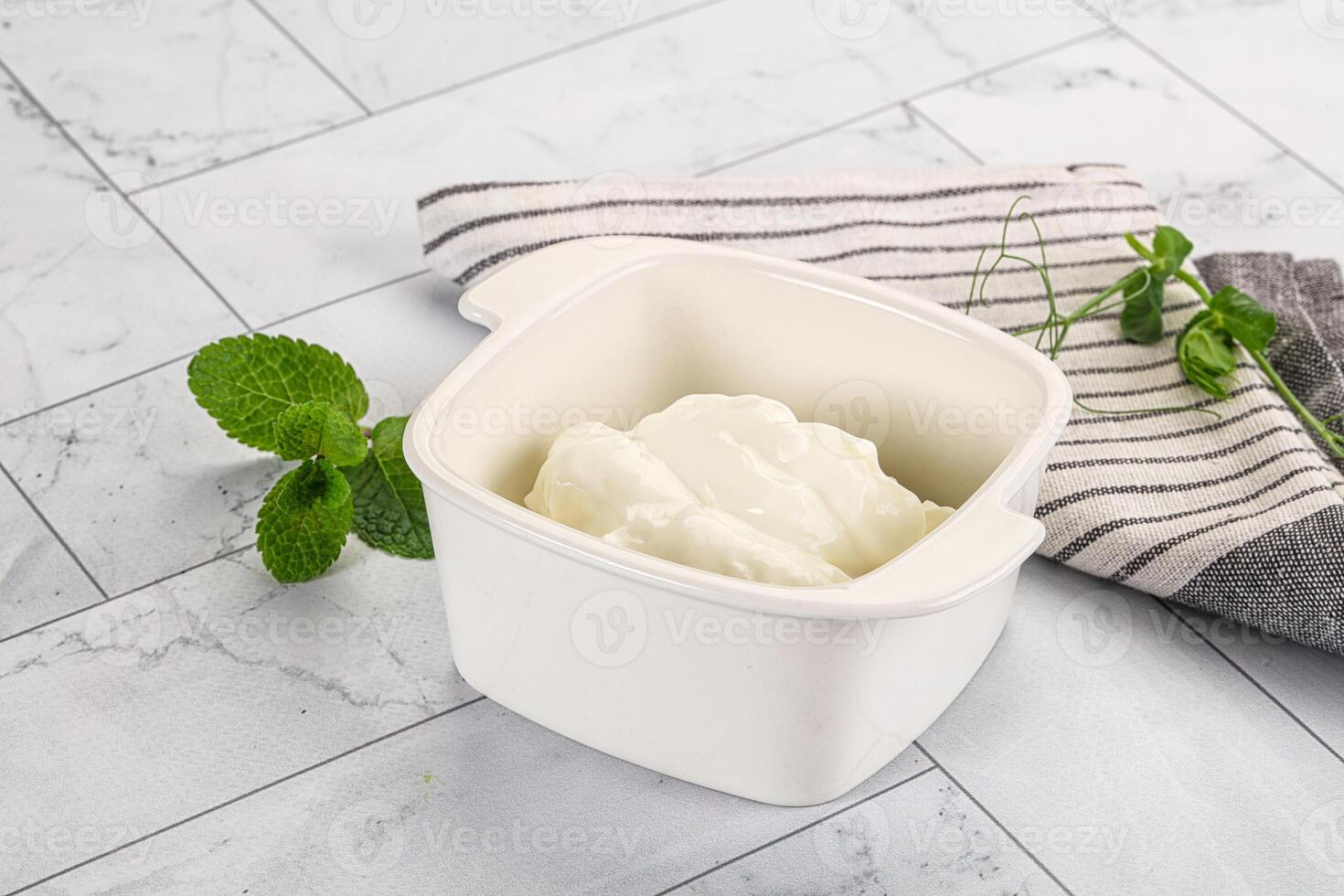 A bowl of yogurt sits on a counter next to a towel photo