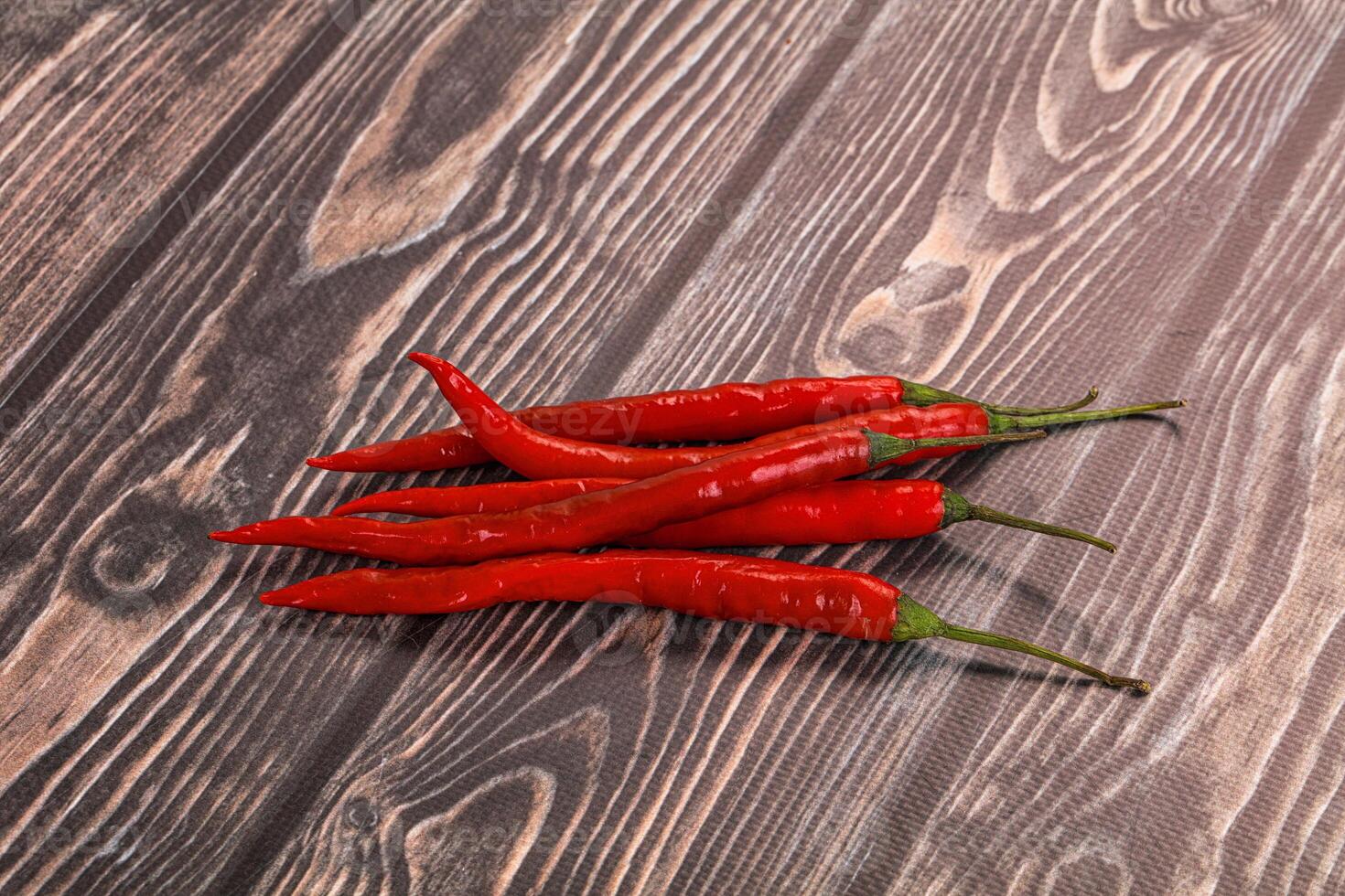 Three red hot peppers on a wooden table photo
