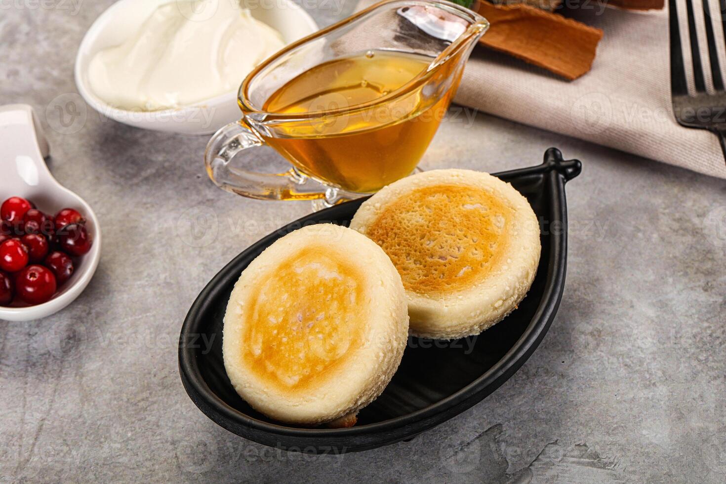 A plate with two pancakes and a bowl of syrup photo