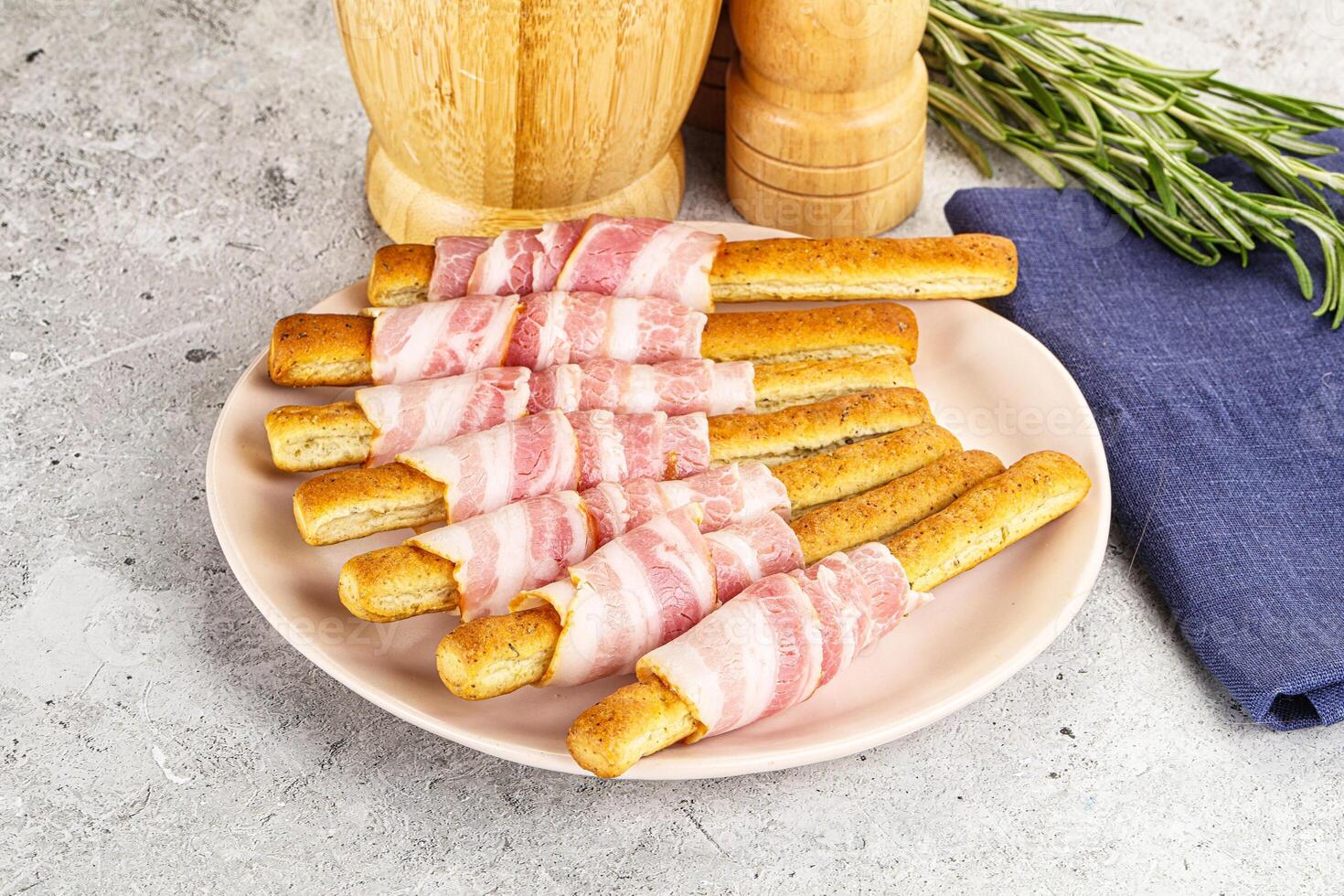 A plate topped with bacon wrapped bread sticks photo