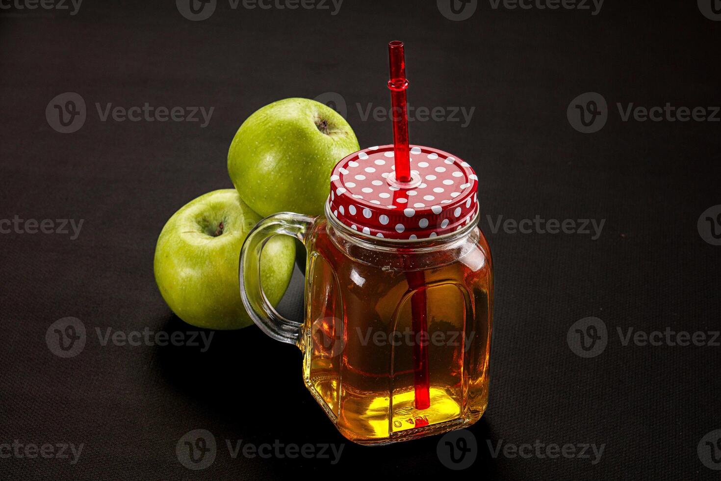 A jar of apple juice and two green apples photo