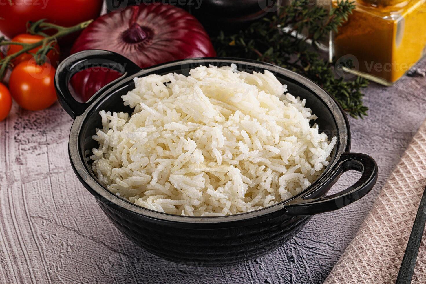 A bowl of white rice next to a knife and other vegetables photo