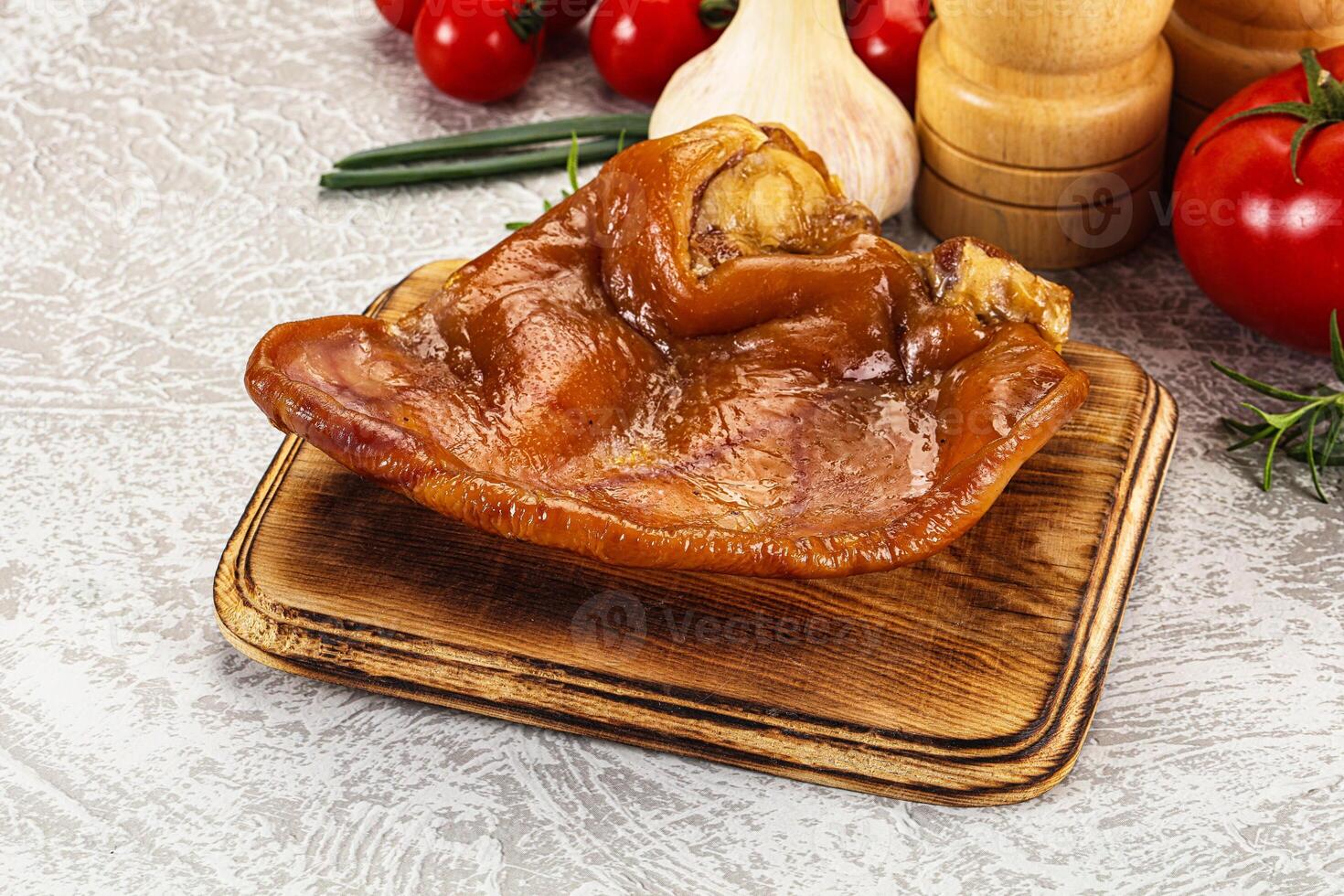 A piece of meat on a cutting board with a knife and a pepper photo