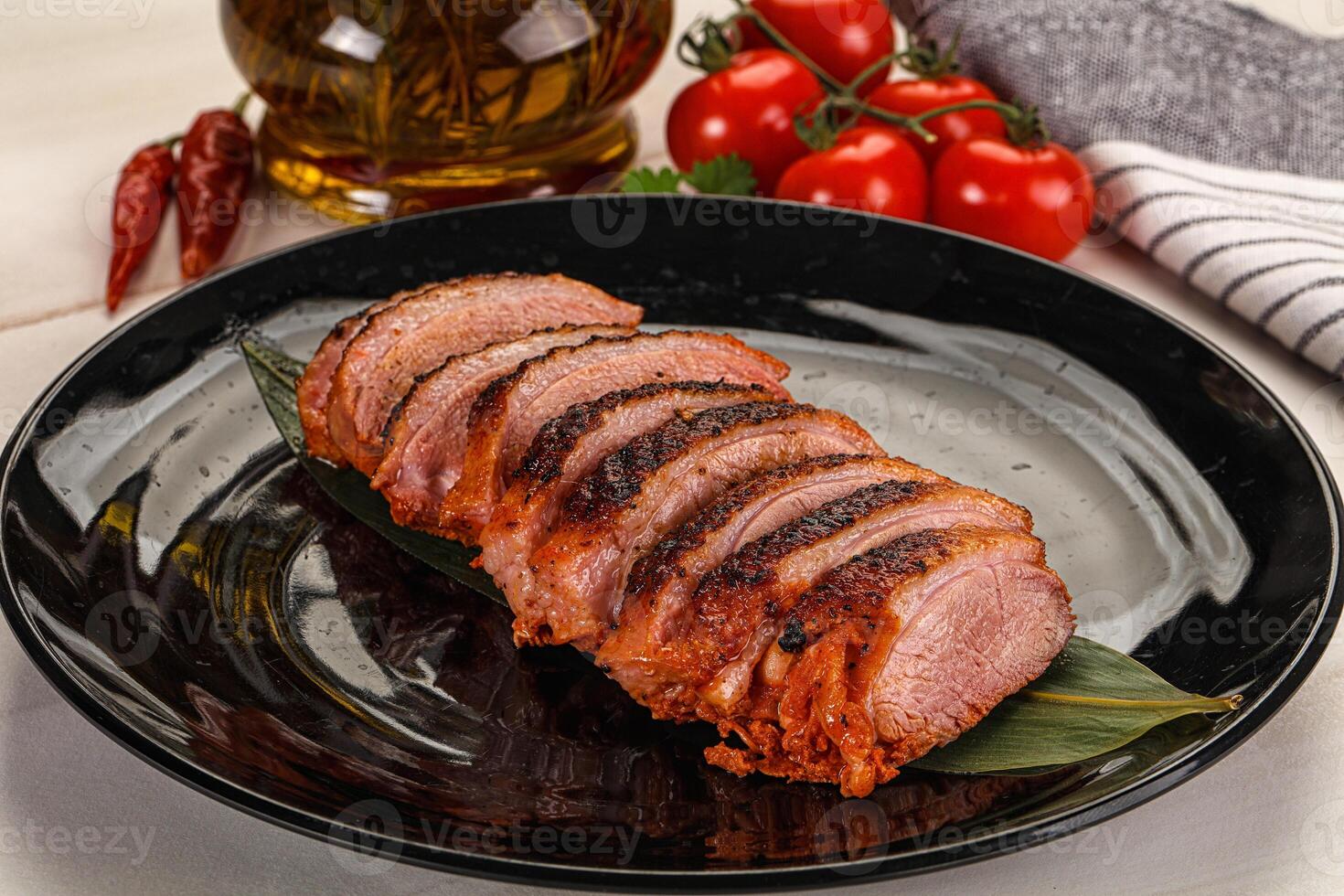 A plate of meat on a table with a bottle of oil photo