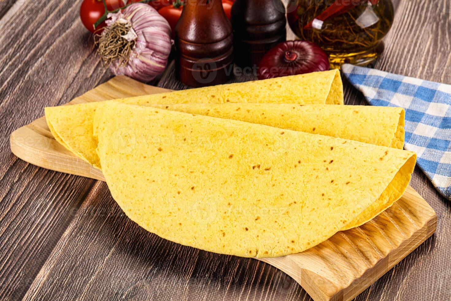 A tortilla on a cutting board with tomatoes and other ingredients photo