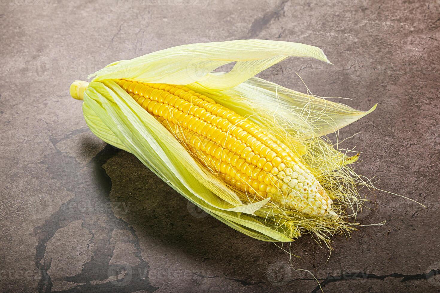 A corn on the cob on a concrete surface photo