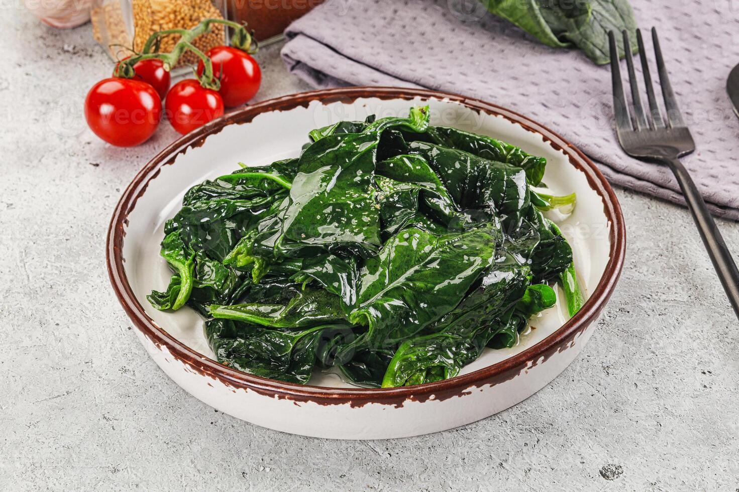 Spinach in a bowl with a fork and tomatoes photo