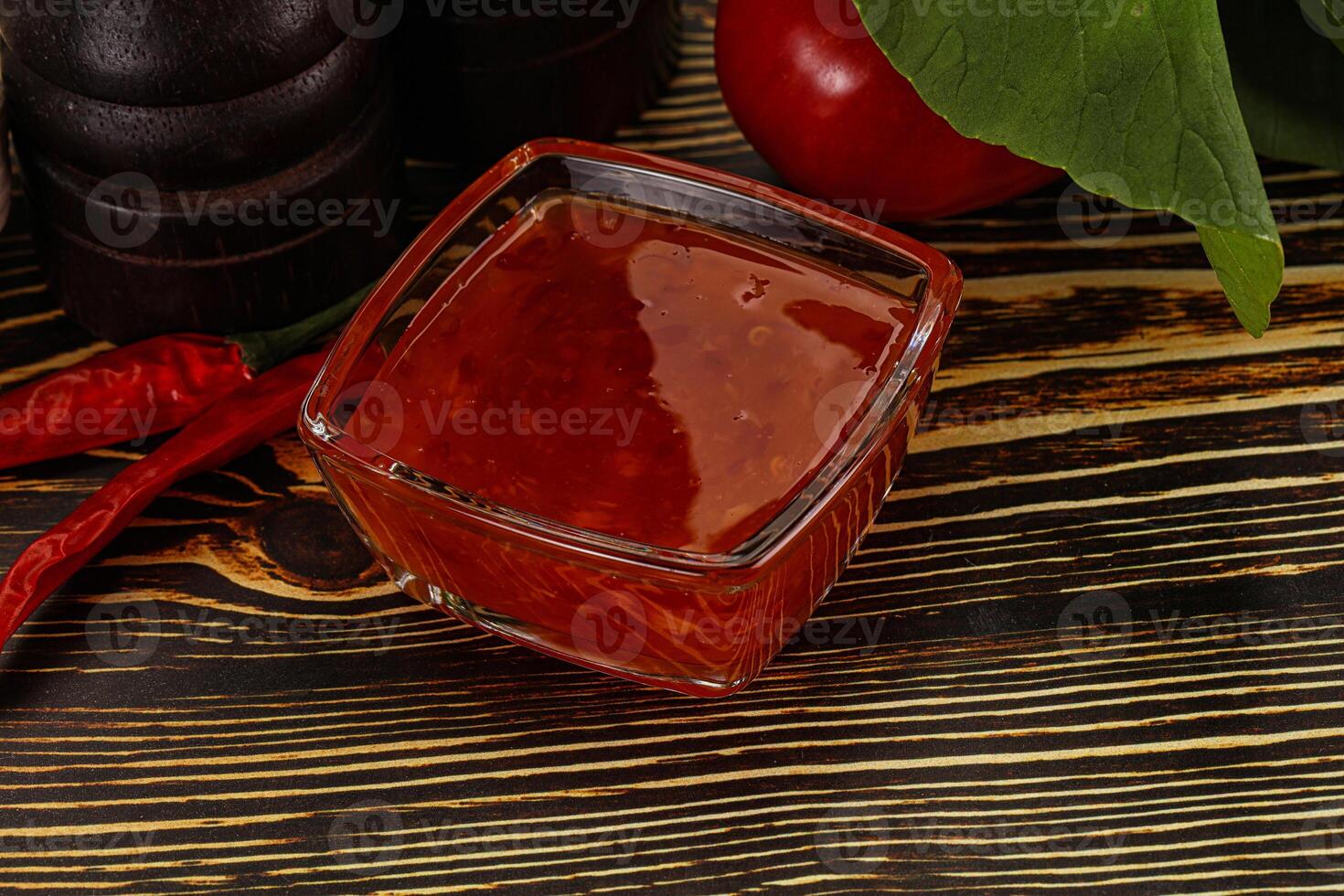 A glass of red liquid next to a bowl of chili peppers photo