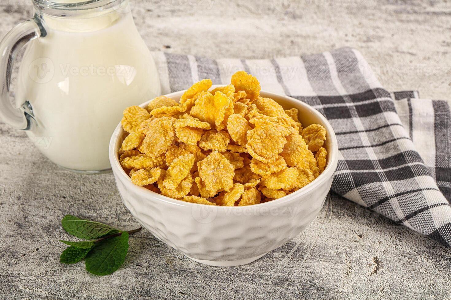 A bowl of corn flakes and a glass of milk photo