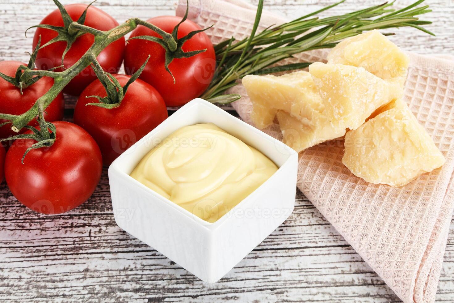 A bowl of cream cheese next to tomatoes and a piece of bread photo