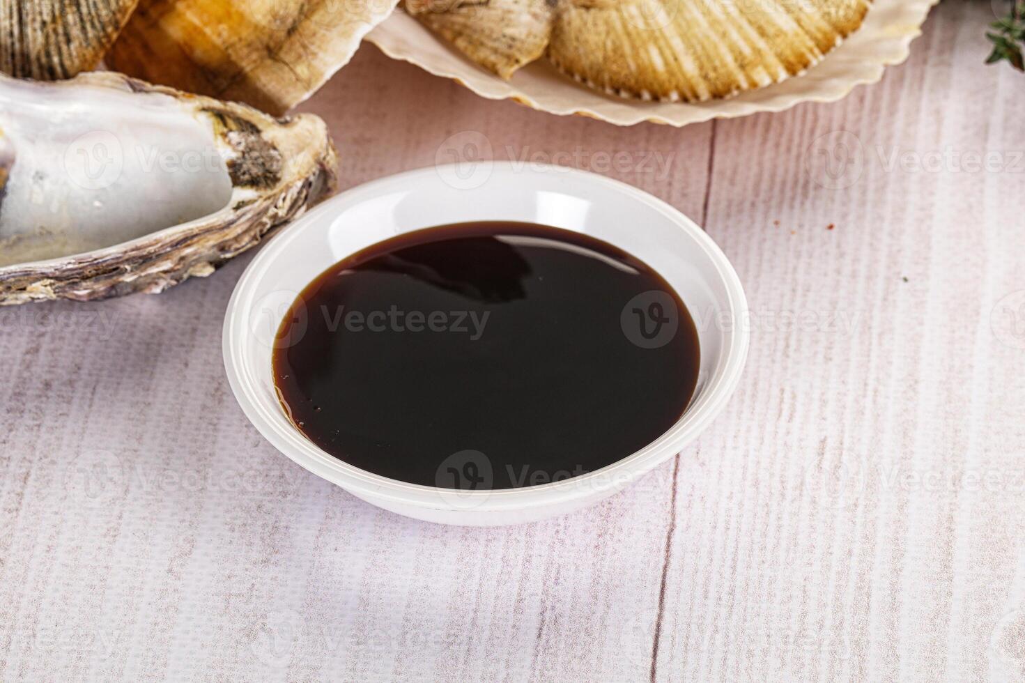 A bowl of sauce next to a bowl of oysters photo