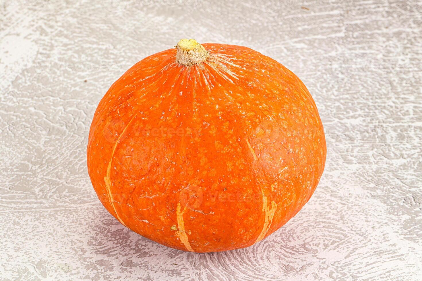 A small orange pumpkin on a white surface photo