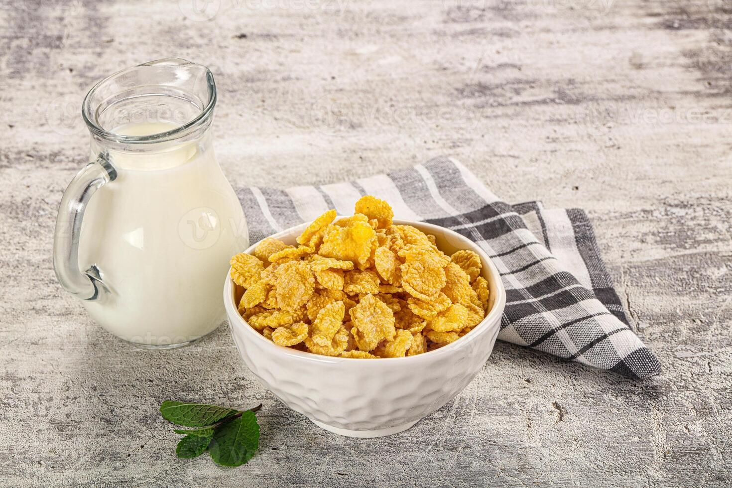 A bowl of cereal next to a glass of milk photo