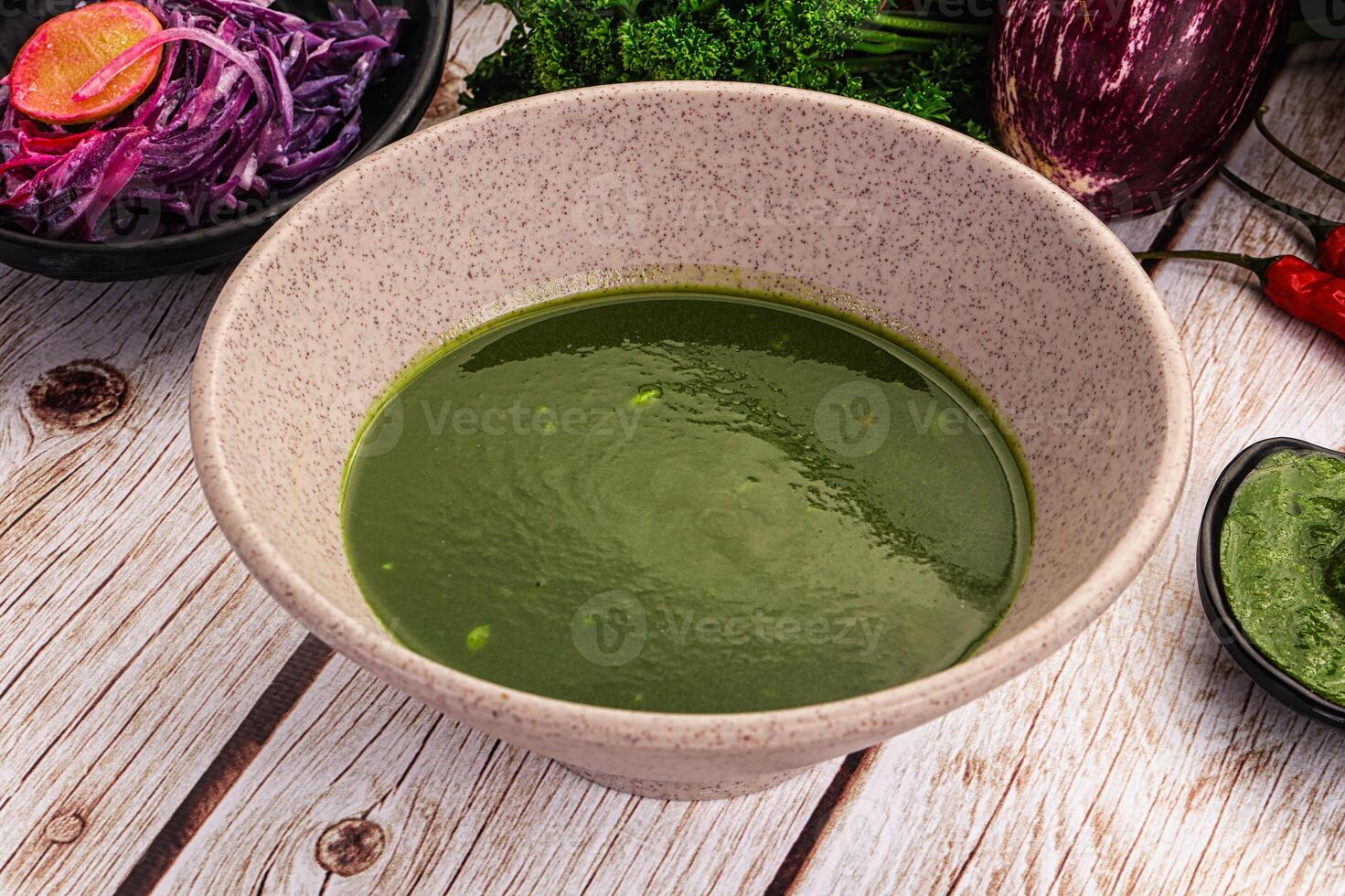 A bowl of green soup next to a bowl of red soup photo